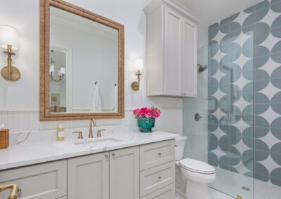 Elegant bathroom with a white vanity, gold accents, and patterned shower tiles